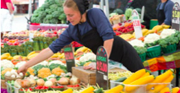 Women leanining over a fruit stand