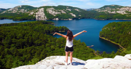 Girl standing at the top of a mountain overlooking a lake