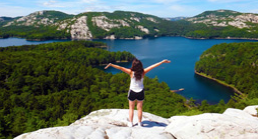 Girl standing onto of a mountain overlooking a lake