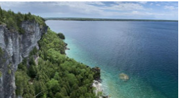 Ariel view of clear blue water and forested cliffs