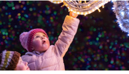 Little girl reaching up for a Christmas light