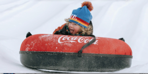 Boy going down a hill on a snow tube