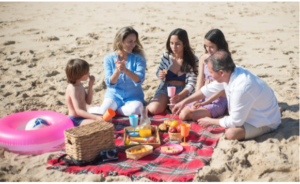 A family sitting on the beach having a picnic 