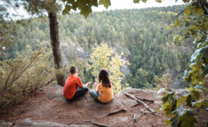 Two children sitting on a cliff in a forest