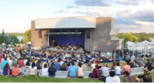 People sitting on a lawn in front of a stage